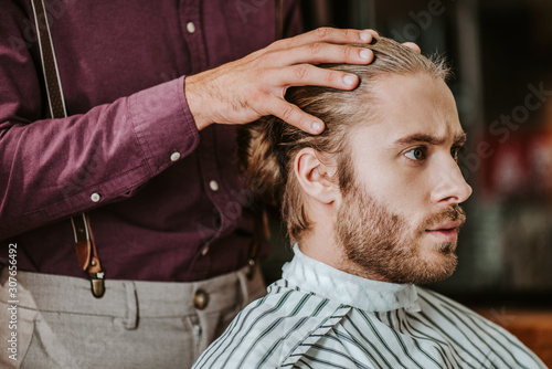 barber putting hands on hear of handsome bearded man