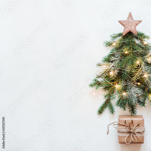 Christmas tree made of fir branches with wooden star and paper lace gift. Zero Waste Christmas concept