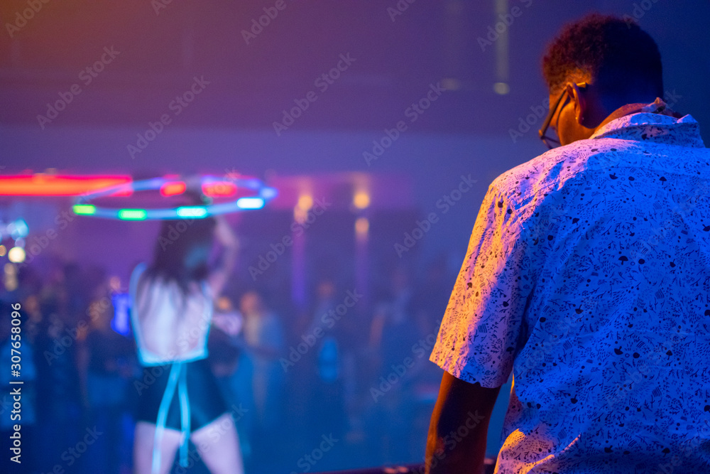 Concert shot featuring DJ, crowd, and a dancer