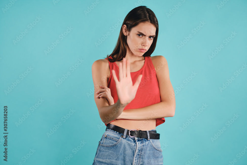 Angry casual girl sadly looking in camera showing stop gesture over colorful background isolated Angry casual girl sadly looking in camera showing stop gesture over colorful background isolated