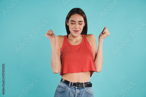 Pretty joyful casual girl happily closing eyes rejoicing on camera over colorful background isolated