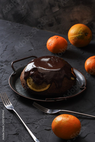 Homemade winter dessert. Sweet chcocolate pudding with oranges and tangerines on black background copy space. Low key still life photo