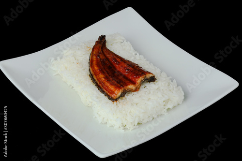 kabayaki or unagi topping many rice on white dish is delicious  on black background photo