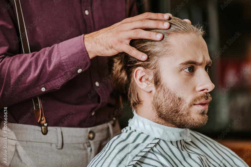 Fototapeta premium barber putting hands on hear of handsome bearded man