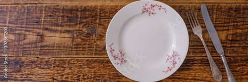Plate and cutlery on the background of vintage wooden boards. Vintage background and space for text. View from above. Flat lay. Cutlery. Banner.