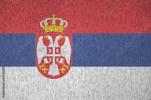 Serbia flag depicted in bright paint colors on old relief plastering wall. Textured banner on rough background photo