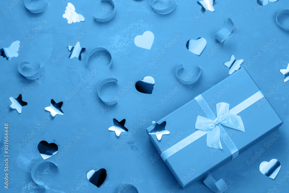blue present box with bow on a blue background with confetti blue present box with bow on a blue background with confetti