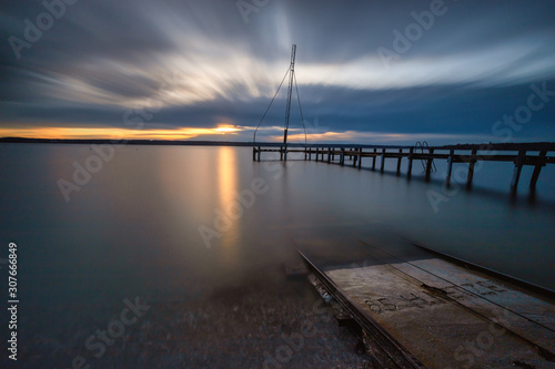 Sonnenuntergang am Ammersee mit Steg und Schienen die ins Wasser führen