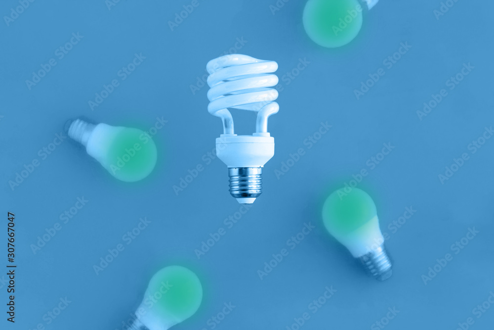 levitating spiral energy saving light bulb and flying bulbs on blue background, energy saving and eco friendly life concept levitating spiral energy saving light bulb and flying bulbs on blue background, energy saving and eco friendly life concept