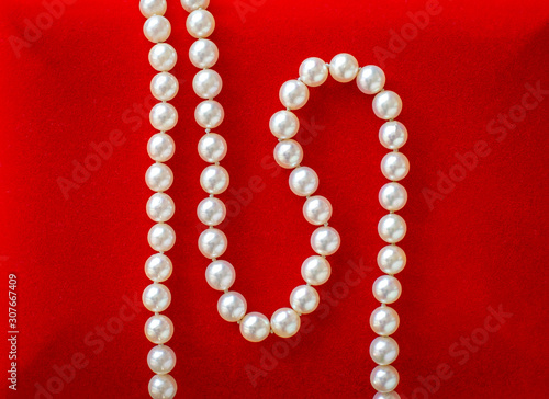 Beautiful natural pearl necklace laid on red velvet jewelry box.