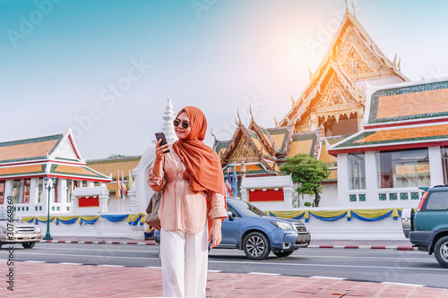 Photography Confident muslim Woman tourist walking in the buddha temple, Asian woman using cell phone in road