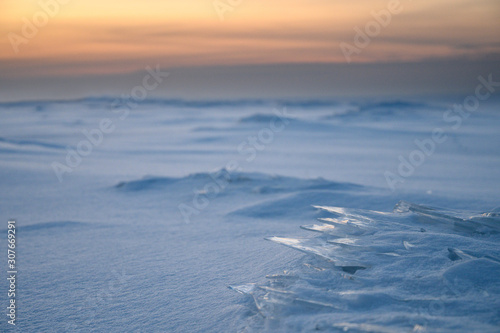 Ice plates on the surface of a frozen bay at sunset.