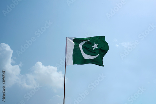 The national flag of Pakistan flying in the blue sky with clouds