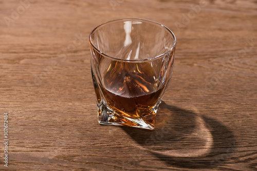 Glass of brandy with shadow on wooden table