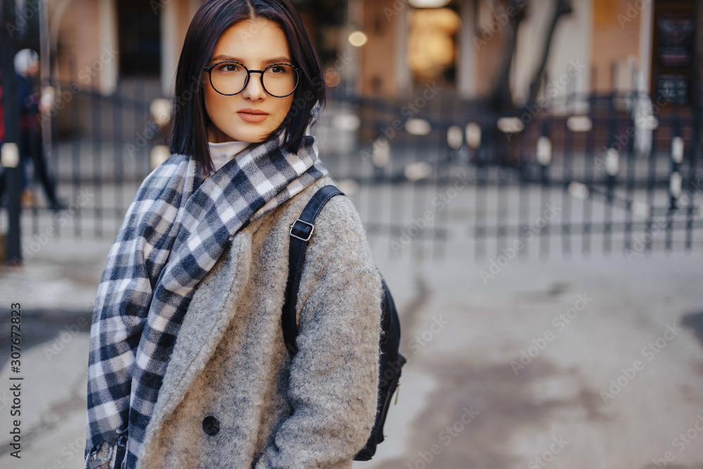 Attractive young girl wearing glasses in a coat walking on a sunny day Attractive young girl wearing glasses in a coat walking on a sunny day