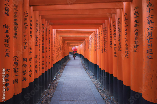 Photography An Asian woman wearing Japanese traditional kimono standing in Fushimi Inari Taisha during travel holidays vacation trip outdoors in Kyoto, Japan