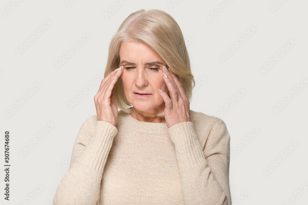 Headshot of old woman having terrible headache with eyes closed Headshot of old woman having terrible headache with eyes closed