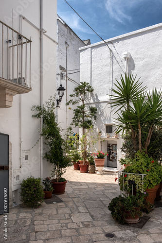 Small deserted courtyard, plants in pots. Old town, white Locorotondo, Italy.