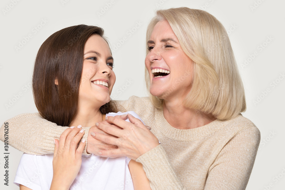 Laughing mature mother embracing happy millennial daughter spending time together Laughing mature mother embracing happy millennial daughter spending time together