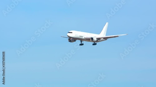 Generic Air Cargo Freighter Airplane Flying in a Blue Sky over Mountains during Final Approach on a Sunny Day