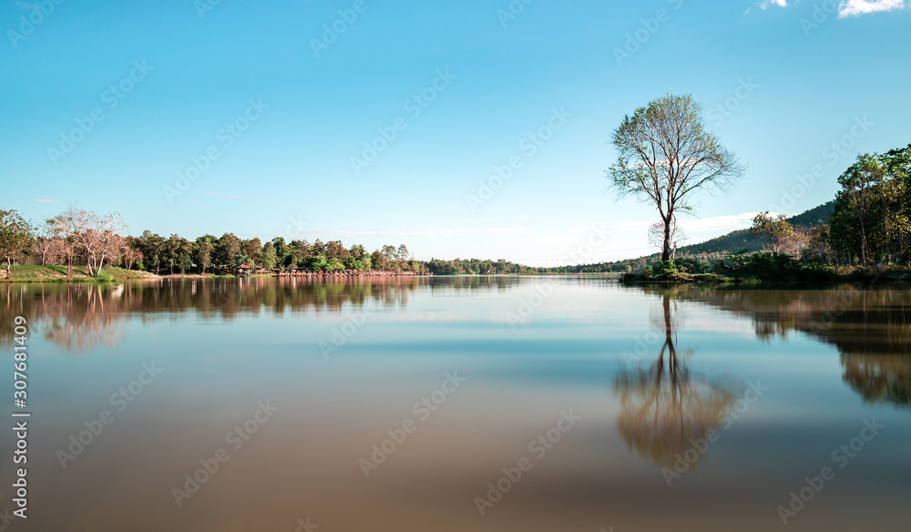Obraz premium Peaceful tree reflection on lake of Huay Tung Tao lake at Chiang Mai, tourist camping vacation resort near beautiful calm water nature background in sunny day
