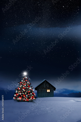 Glänzend leuchtender Christbaum im Schnee bei einer Holzhütte mit leuchtendem...