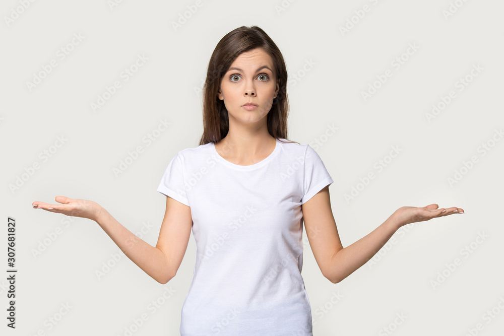 Confused young woman shrug as sign of doubt making choice Confused young woman shrug as sign of doubt making choice