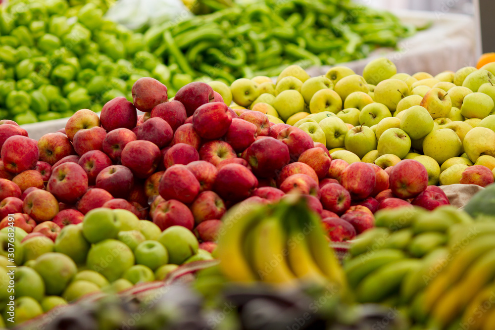 Red, green, yellow apples and other fruits on display at farmer's market