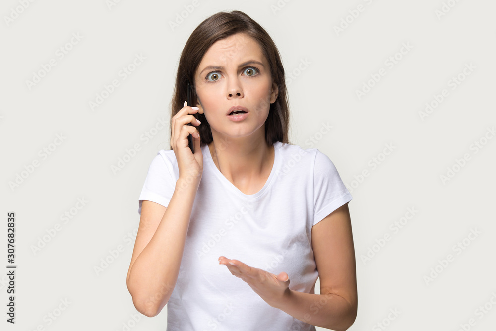 Headshot of shocked millennial woman having argument talking via smartphone Headshot of shocked millennial woman having argument talking via smartphone