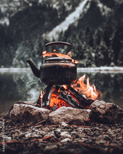Cooking hot warming tea at the cozy campfire the lake