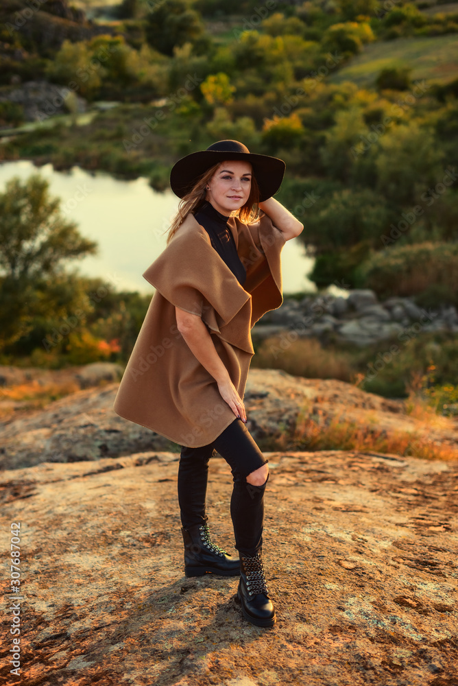 Attractive girl with long blonde hair in black hat and on a background ...