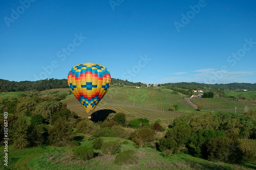 A hot air balloon dipping downward with the air drafts in Napa valley.