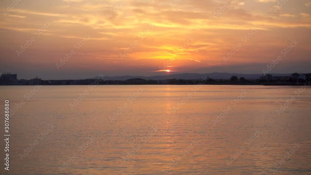 Bright sunset over the sea in slow motion with city silhouettes on the horizon Bright sunset over the sea in slow motion with city silhouettes on the horizon