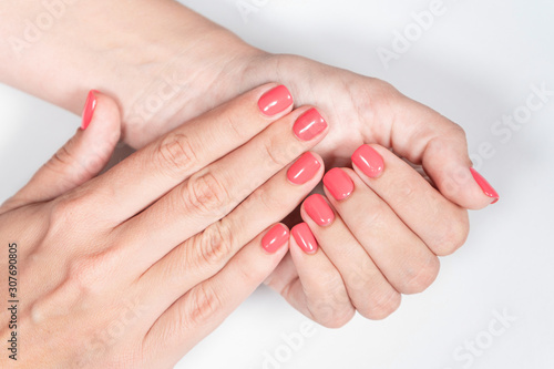 Closeup view of beautiful female hands with painted nails. Fingernails with modern trendy one color bright pink manicure. Horizontal color photography.