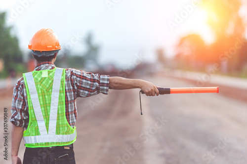 Worker with light stick on road construction background