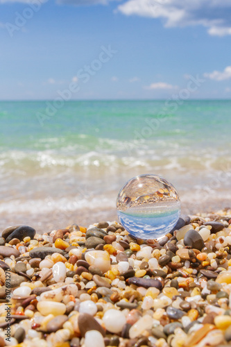 Glass round ball on the beach reflects the sea in summer