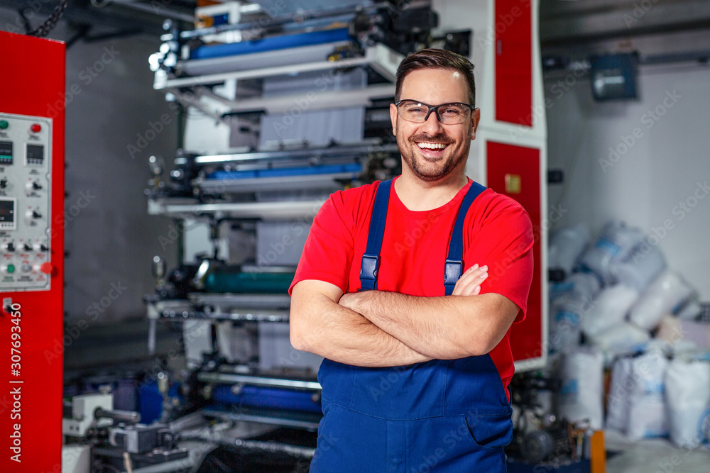 Cheerful factory worker with arms crossed. - obrazy, fototapety, plakaty 