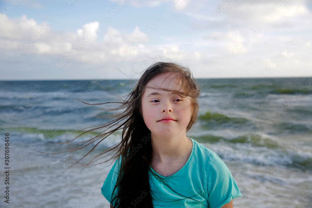 Portrait of down syndrome girl smiling on background of the sea