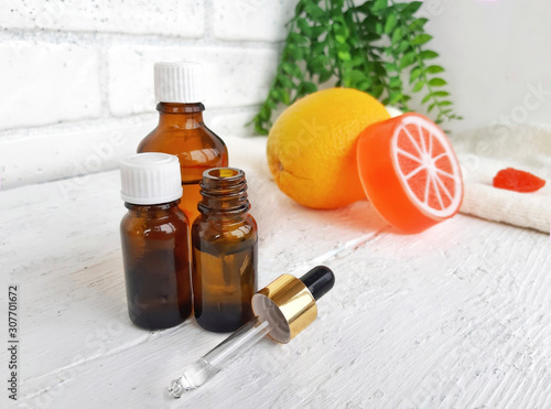Fototapeta Naklejka Na Ścianę i Meble -  Aroma essential oil bottles with orange citrus soap on white wooden background. Spa arometherapy and alternative medicine concept.