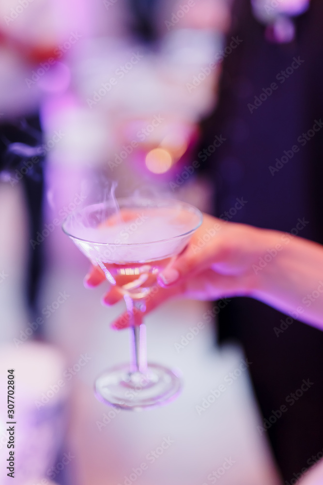 The bride holds a glass with champagne in her hand. Close-up shot of hands, tossing glass of alcohol at a party or event.