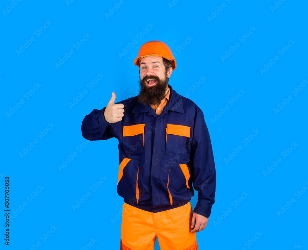 Construction worker in hard hat. Mechanical worker in uniform shows thumb up. Bearded man in suit with construction helmet. Smiling builder in uniform with thumb up. Business, industry, technology. Construction worker in hard hat. Mechanical worker in uniform shows thumb up. Bearded man in suit with construction helmet. Smiling builder in uniform with thumb up. Business, industry, technology.