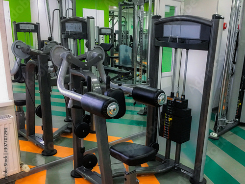 Gym or fitness hall interior with equipment. Machines, barbells, rods, disks, weight, dumbbells. Sport, bodybuilding, lifestyle and people concept