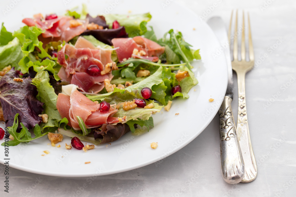 salad prosciutto with pomegranate on white plate salad prosciutto with pomegranate on white plate
