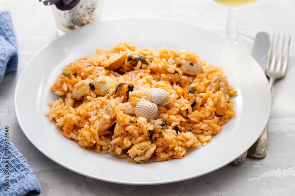 rice with seafood on white plate on ceramic background