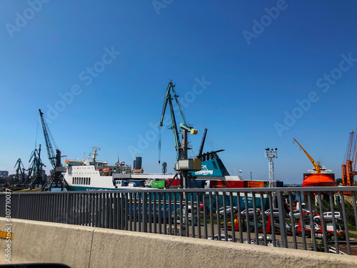 Batumi, GEORGIA - - July 29, 2019: Cranes near the ship in port. Big gate near the port of seaside. Sunny day in the city