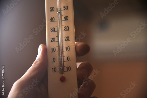 Tableau sur toile hand with a white plastic mercury thermometer shows the temperature in the room