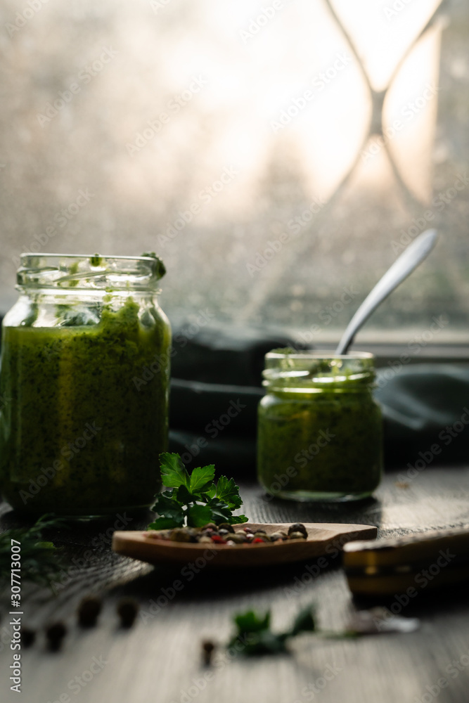 Homemade parsley pesto sauce and ingredients on a windowsill with parsley leaves Homemade parsley pesto sauce and ingredients on a windowsill with parsley leaves