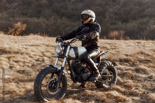 The single man-equipped  motorcyclist drives in the steppe  wearing a helmet  black jacket  gloves  leather pants and boots. Hobby  extreme occupation  recreation in nature  freedom.