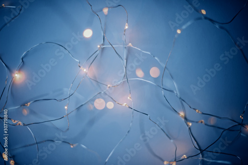 Blurry luminous warm white garland in blue tones. New Year Christmas background.