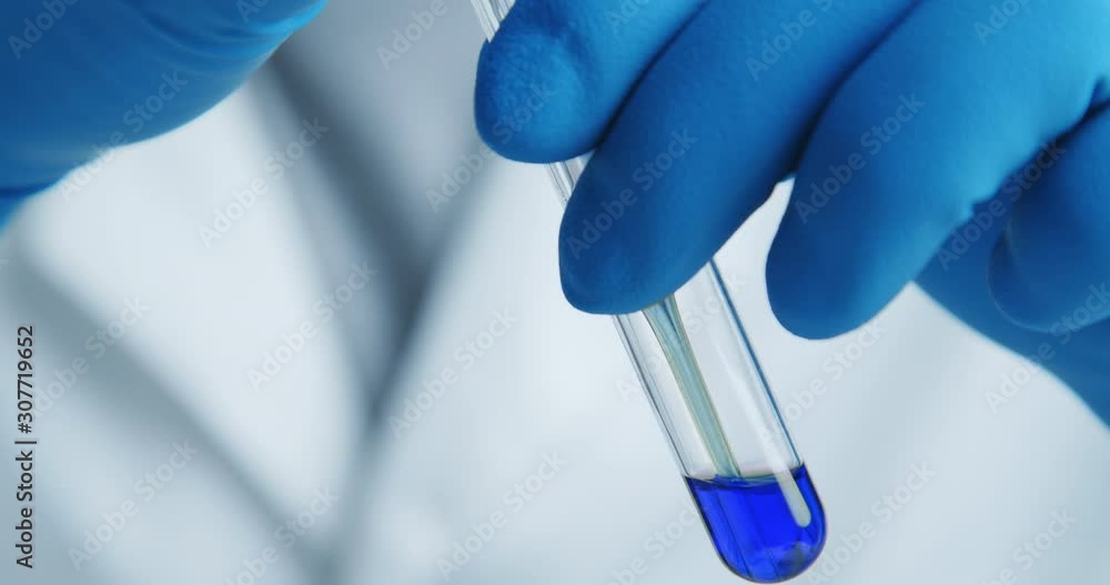 Close-up shot with hitting laboratory equipment. Blue liquid falling pipette in glass test tube. Close-up shot with hitting laboratory equipment. Blue liquid falling pipette in glass test tube.